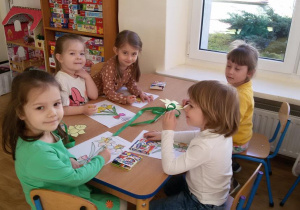 Widok na siedzące przy stoliku dzieci, które kolorują żonkile.